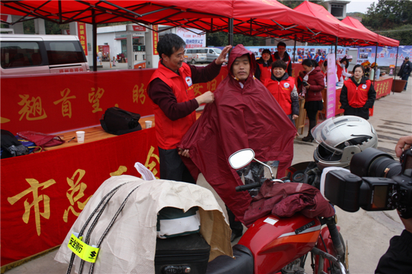 梧州市總工會(huì)的黨員義工們?cè)谑袞|出口春運(yùn)服務(wù)站助力“摩托大軍”平安返鄉(xiāng)，幫助他們檢查車輛和行李，穿上雨衣。--黃賀峰攝.j